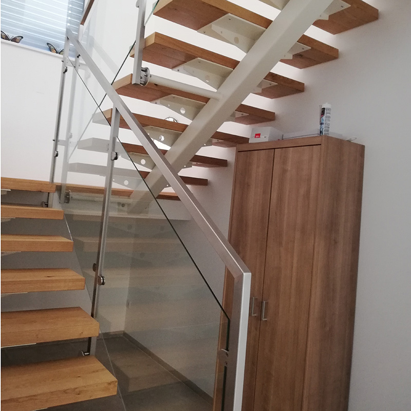 Innenaufnahme einer modernen Holztreppe mit Glasgeländer und Metallrahmen