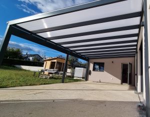 Neue stabile Terrassenüberdachung mit anthrazitfarbenem Metallrahmen und lichtdurchlässigen Polycarbonatplatten auf Betonboden