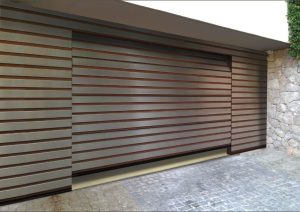 Moderne Garage mit seitlich öffnendem Tor in horizontaler Holzlamellenoptik, passend zur Natursteinfassade.