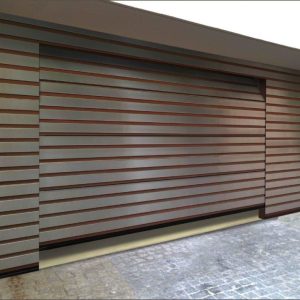 Moderne Garage mit seitlich öffnendem Tor in horizontaler Holzlamellenoptik, passend zur Natursteinfassade.