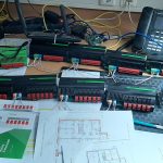 Mehrere Loxone Relay Extensions und Steuerungsmodule verkabelt auf einem Arbeitstisch im Testaufbau bei FuMa OG, mit Schaltplänen und Laptop für Smart Home Installation.