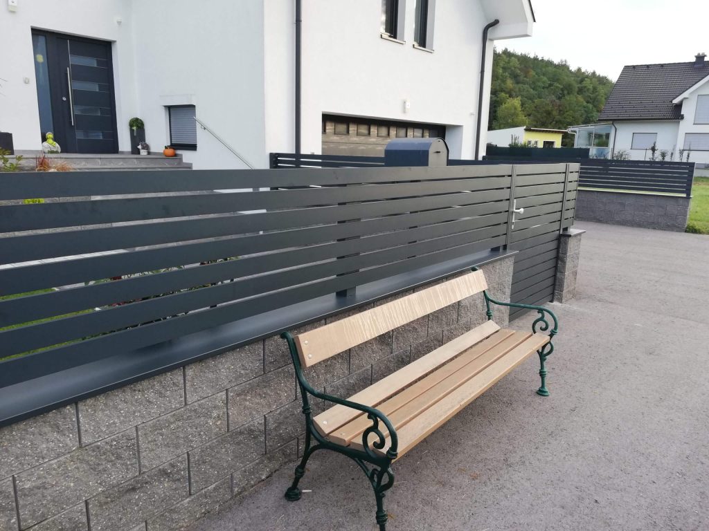 Anthrazitfarbener Aluminiumzaun mit waagerechter Lamellenstruktur vor einem Einfamilienhaus – langlebiger Sichtschutz mit moderner Optik, geeignet für automatisierte Zugangslösungen von FuMa OG